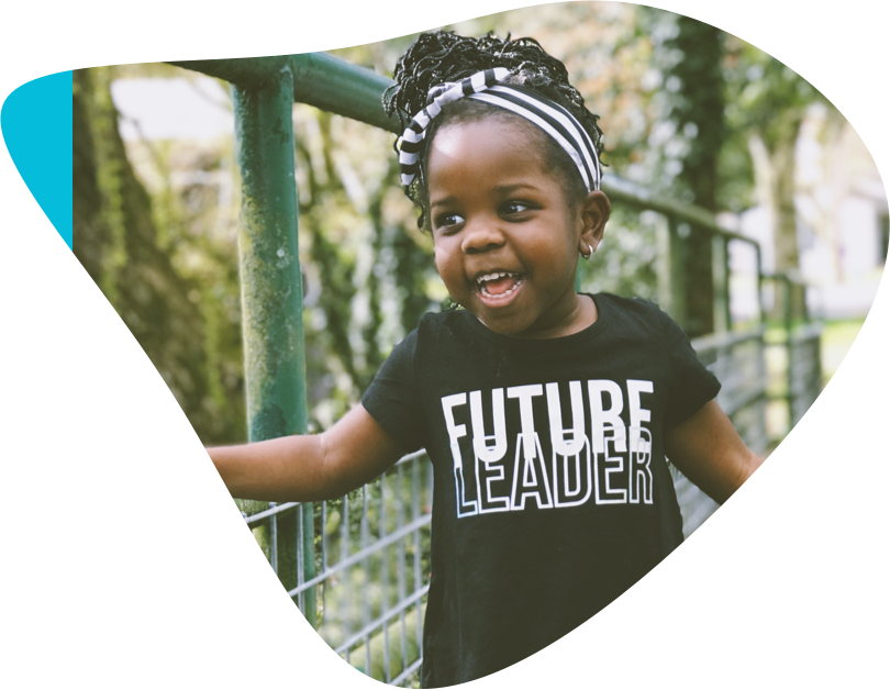 Smiling little girl stands on bridge wearing a teeshirt that reads “Future Leader”