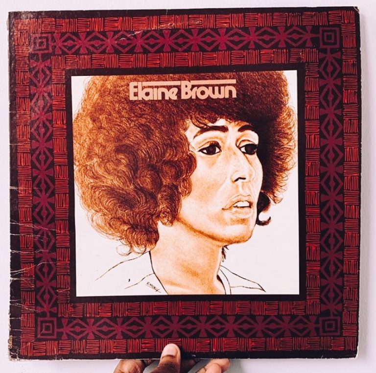 A hand holds a vintage record with a graphic photo illustration of Elaine Brown and text that reads "Elaine Brown"