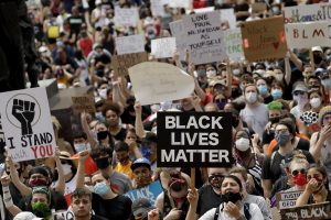 In this June 5, 2021 photo, people hold signs as they listen to a speaker in front of city hall in downtown Kansas City, Mo., during a rally to protest the death of George Floyd who died after being restrained by Minneapolis police officers on May 25.