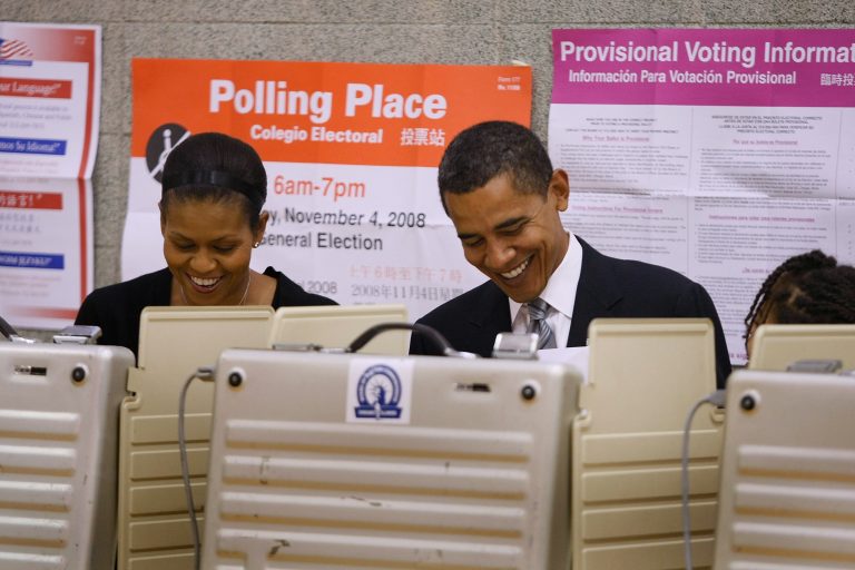 Smiling and side by side, Michelle and Barak Obama fill out voting ballots behind several privacy screens.